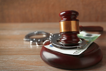 Law gavel with euro and handcuffs on wooden table background, closeup