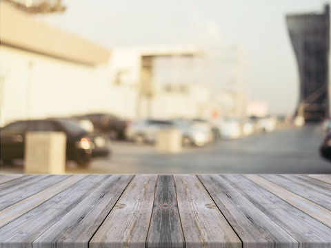 Wooden board empty table blurred background. Perspective grey wood over blur car park outdoor - can be used for display or montage your products. Mock up for display of product. Vintage filter image.