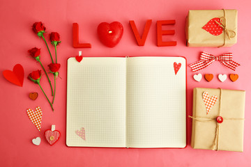 Notebook with gift and Valentine's decor on pink background, top view