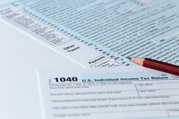 Obraz premium 1040 Individual Income Tax Return Form for 2015 year with a pencil to fill on the white desk, close up