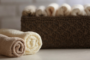 Wicker basket with towels inside on wooden table background