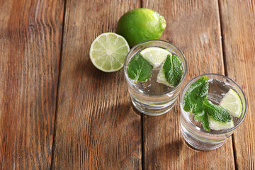Fresh cocktails with mint, ice and lime on wooden table background