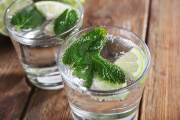 Fresh cocktails with mint, ice and lime on wooden table background
