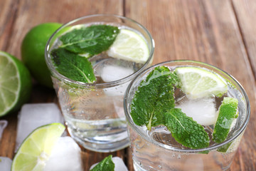 Fresh cocktails with mint, ice and lime on wooden table background