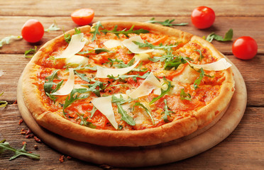 Margherita pizza with tomatoes, Parmesan and arugula on wooden background