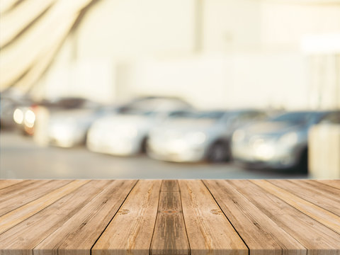 Wooden board empty table blurred background. Perspective brown wood over blur car park outdoor - can be used for display or montage your products. Mock up for display of product. Vintage filter image.