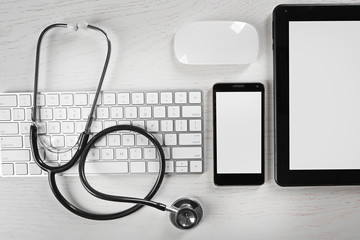 Tablet, phone, keyboard and stethoscope on the table, top view