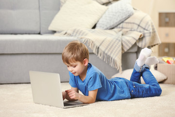 Little boy using laptop on carpet indoors © Africa Studio