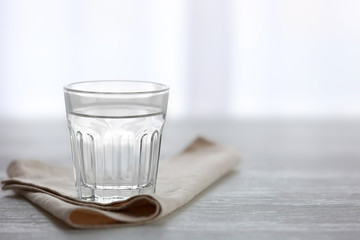 Glass of water with napkin  on wooden background
