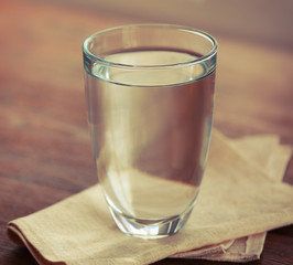 Glass of water with napkin  on wooden background