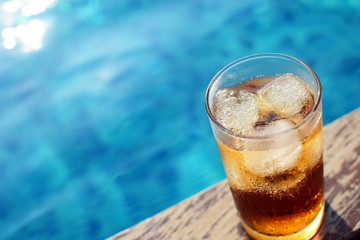 A glass of ice cola at pool with vintage filter background