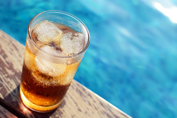 A glass of ice cola at pool with vintage filter background