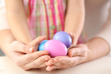 Hands of mother and daughter holding painted Easter eggs closeup