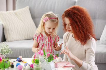 Mother and daughter decorating Easter eggs, indoors
