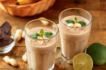 Fresh banana cocktail with peanuts and chocolate on wooden table