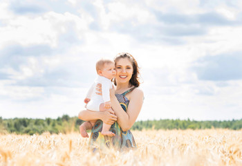 Beautiful woman playing with her infant baby in a meadow of whea