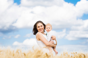 Obraz premium Beautiful woman playing with her infant baby in a meadow