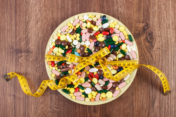 Tablets or supplements on plate wrapped centimeter, health care and slimming concept