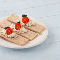 Dry diet crisp breads with cheese, cherry tomatoes and olives