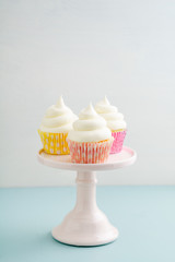 Three cupcakes with buttercream frosting on a cake stand