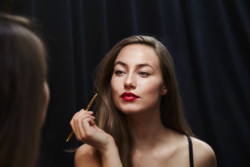 Obraz premium Glamorous girl with red lipstick looking in mirror