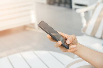 Woman typing text message on smart phone in a cafe. Cropped image of young woman sitting at a table with a coffee using mobile phone.
