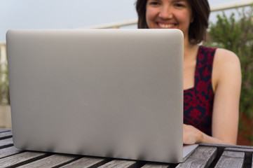 Smiling young woman and laptop outdoors