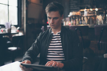Young casual fashion man with tablet in cafe