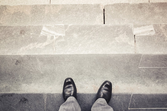 Male feet stand on outdoor stone stairs