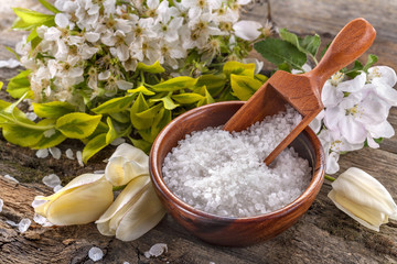 Fototapeta na wymiar Sea bath salt in bowl with flowers on rustic table