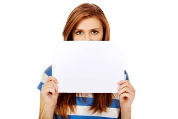 Teenage woman covering face with blank card 