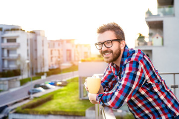 Businessman with cup of coffee standing on balcony, relaxing