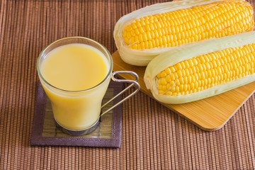 Corn milk in glass, kernel corn in bowl and fresh corn