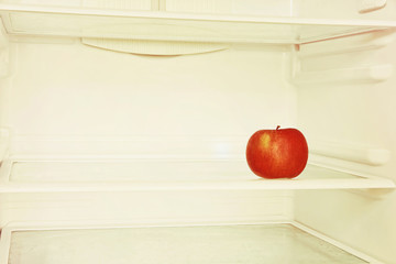 Single red apple in domestic refrigerator taken closeup.