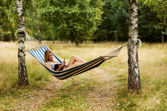 Young woman with tablet on the hammock