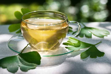 Papier Peint photo Theé glass of herbaceous tea with ginkgo leaves