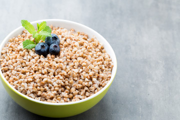 Buckwheat porridge in a bowl with mint leaves and blueberries.