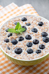 Buckwheat porridge in a bowl with mint leaves and blueberries.