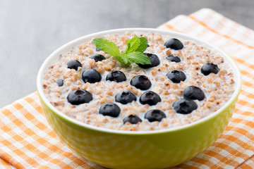 Buckwheat porridge in a bowl with mint leaves and blueberries.