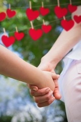 Composite image of mother and daughter holding hands each other 