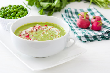 Pea cream with radishes on rustic wood