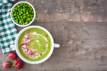 Pea cream with radishes on rustic wood