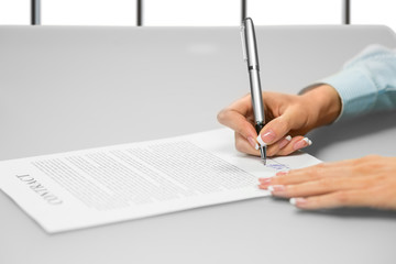 Businesswoman's hand signs a document. Signing paper on white background. One step makes many...