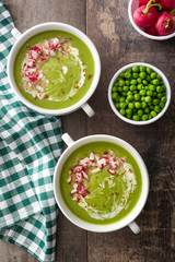 Pea cream with radishes on a rustic wooden background
