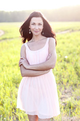 Fototapeta na wymiar Gorgeous brunette woman with dark hair pink dress summer park green meadow bright sun fashion style concept holiday pose