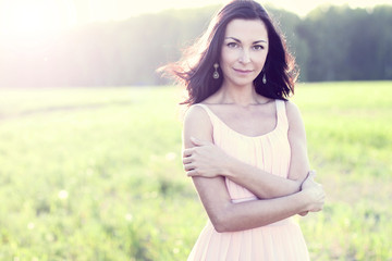 Fototapeta na wymiar Gorgeous brunette woman with dark hair pink dress summer park green meadow bright sun fashion style concept holiday pose