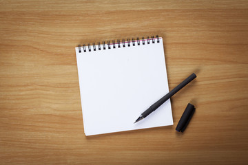 Blank note paper with pen on wood background