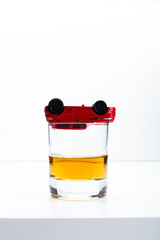 toy car and glass of whiskey metaphor crash accident isolated on white