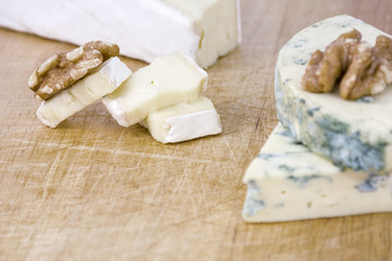 Fototapeta na wymiar Several pieces of cheese roquefort and brie with walnuts on wooden background