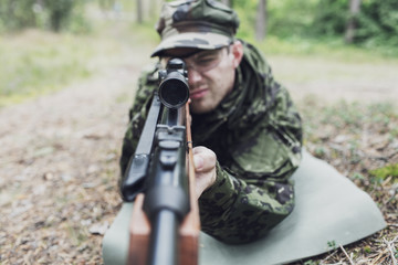 Fototapeta premium close up of soldier or hunter with gun in forest